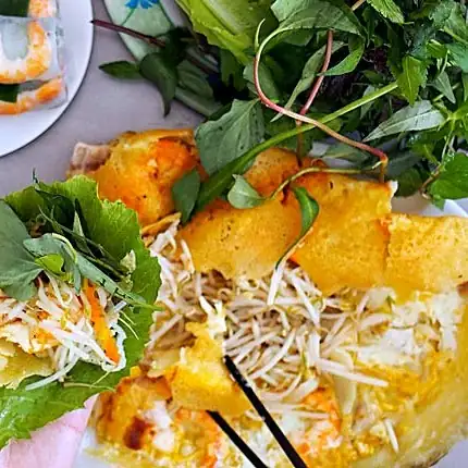 Crispy bánh xèo with lettuce and herbs at Bánh Xèo 46A